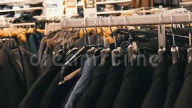 在商场的一家男士服装店，一排暖男`夹克衫在衣架上。 各种男士`西装挂在购物中心